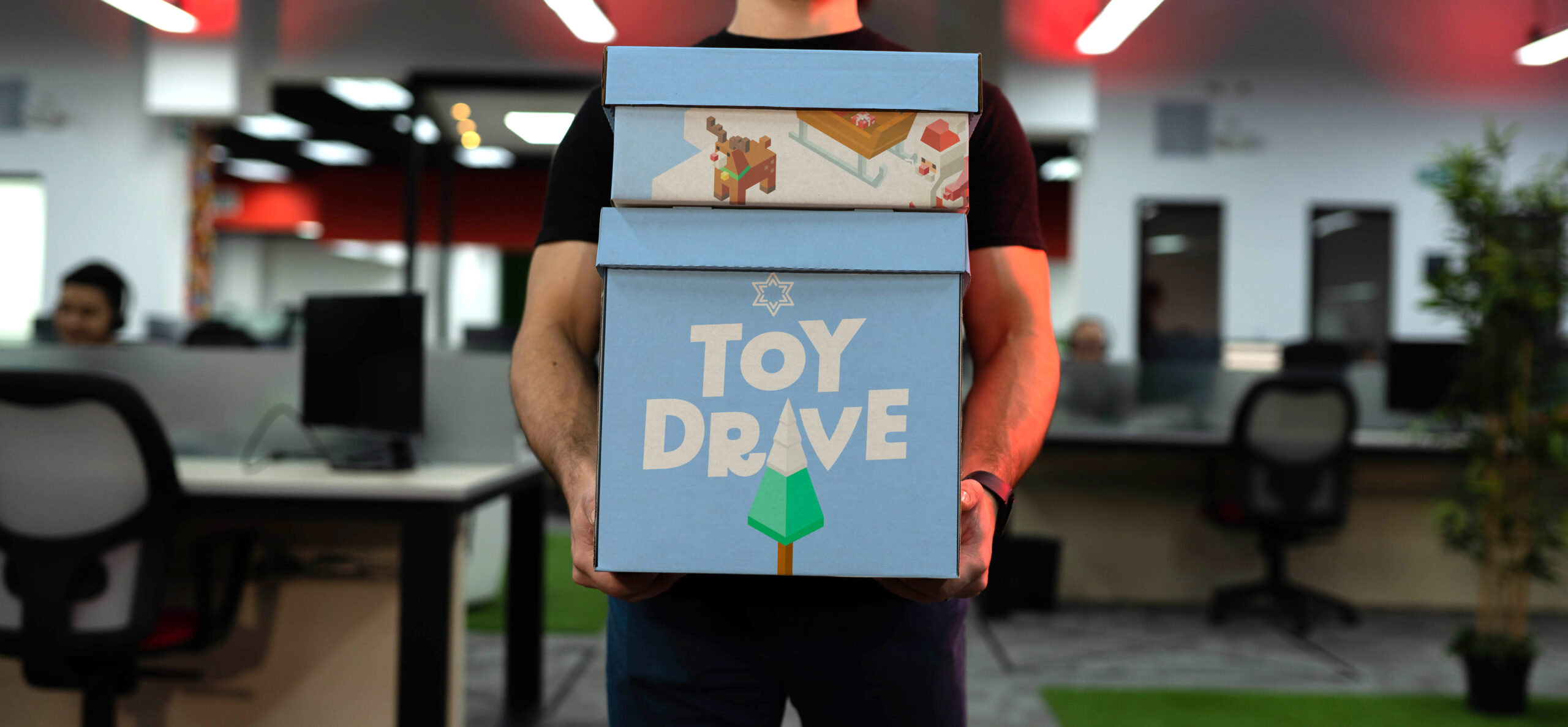 An Applaudo employee holding a box for a toy drive for charity