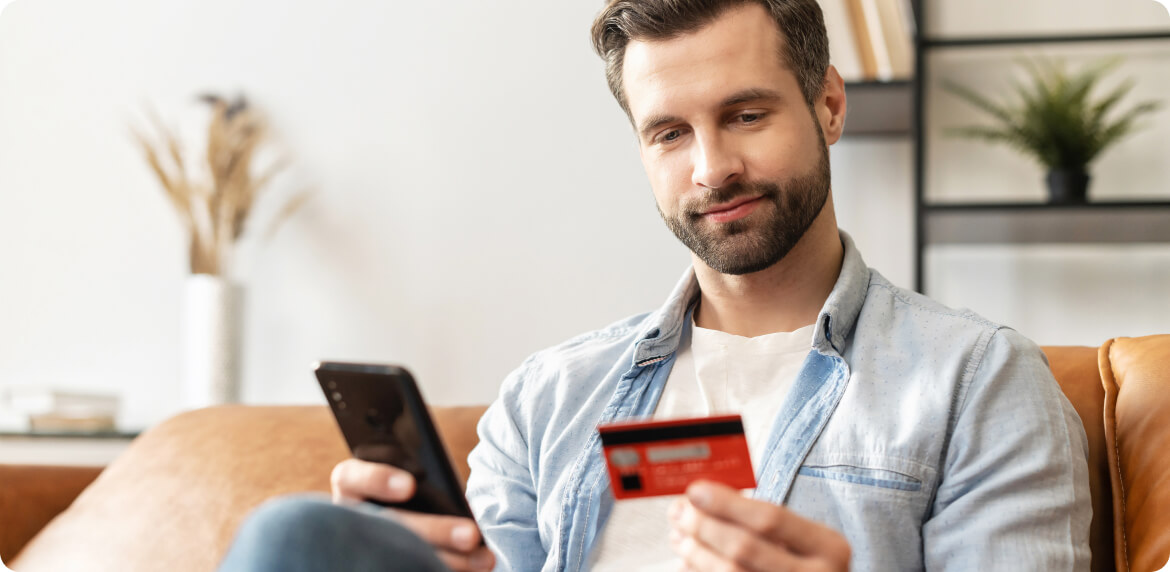 A man making a purchase using a credit card and a mobile phone in a modern setting.