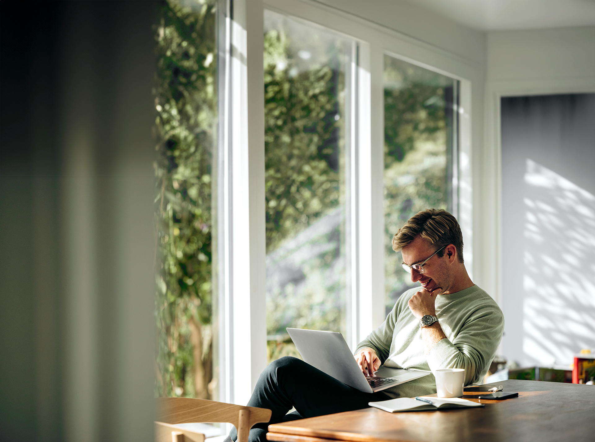 A real estate agent seated at a table, focused on his laptop, engaged in work.